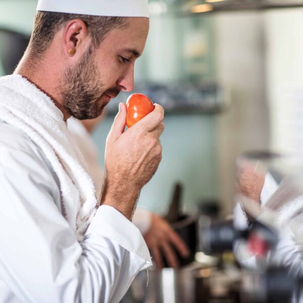 chef-smelling-tomato-in-bright-commercial-kitchen-2026-03-25-01-31-20-utc